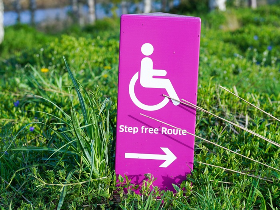 A purple and white sign showing a person in a wheel chair icon with the words Step free route, underneath