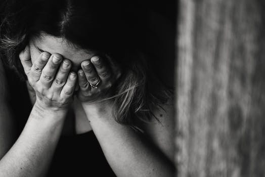 A black and white image of a woman with her head in her hands looking troubled